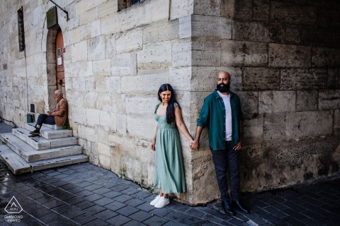 Holding Hands Among Old World Stone Buildings In Eminönü, Istanbul, The Couple Blend Urban Charm With Romance Framed by old world stone buildings in Eminönü, Istanbul, Turkey, the couple walks hand in hand, their pre-wedding session merging urban charm with historic architecture at this striking city scene.