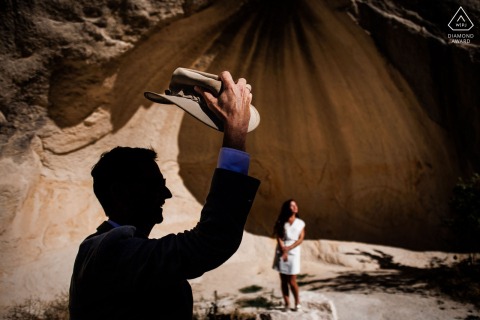 Within a sand rock cave setting at a unique venue near Göreme, Nevşehir, Turkey, the couple is apart, the ancient Cappadocia landscape shaping their pre-wedding photo session in an atmosphere of adventure and intimacy.