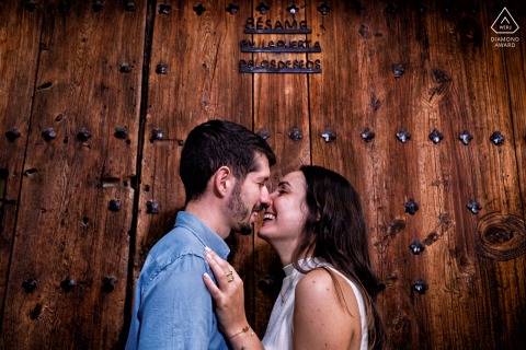 In Cazorla, Jaén, Spain, the couple stands face to face before an old rustic wooden door, their eyes locked and expressions tender as weathered wood and historic woodwork create a timeless backdrop for their pre-wedding photo.