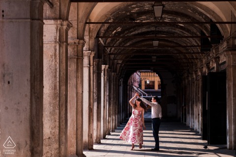 In Venice, Italy, a couple dances beneath the iconic arches, their elegant movements and the timeless architecture of the city combining for an unforgettable engagement portrait full of romance and charm.
