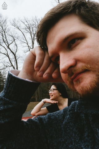 A Maryland engagement portrait shows a couple together by a car, photographed in a straightforward outdoor portrait emphasizing connection and compositional simplicity.