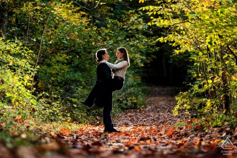 Along a wooded path in Wissahickon Valley Park, Philadelphia, Pennsylvania, one partner lifts the other, framed by surrounding foliage in an outdoor engagement portrait.