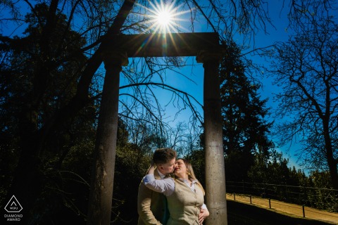 In the gardens of Carmen de los Mártires in Granada, Spain, a couple stands by the fountains, with soft golden-hour light highlighting their expressions in this engagement shot.