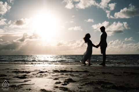 Silhouetted by the soft glow of the early morning sun, a couple stands together at Maceió-AL, Alagoas, Brazil.