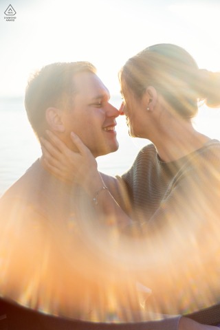 The couple shares a romantic embrace as the sun dips below the horizon at the Lake of Zoug in Switzerland, creating a breathtaking sunset silhouette for their portraits.