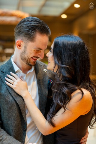 Sitting within the stylish interior of Aigu Restaurant & Bar in Zoug, Switzerland, the couple shares a genuine smile during a relaxed and upscale indoor engagement photography session.