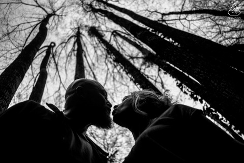 Couple Shares A Quiet Connection Within The Deep Green Forest Of Saint Vincent De Mercuze France Surrounded by the towering, lush trees of Saint Vincent de Mercuze, France, the couple shares a quiet connection within the deep green forest during their scenic pre-wedding session.