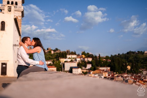 During a romantic session in Slovenia, a loving couple shares an affectionate kiss outdoors, as the photographer emphasizes their deep connection through this timeless engagement portrait.