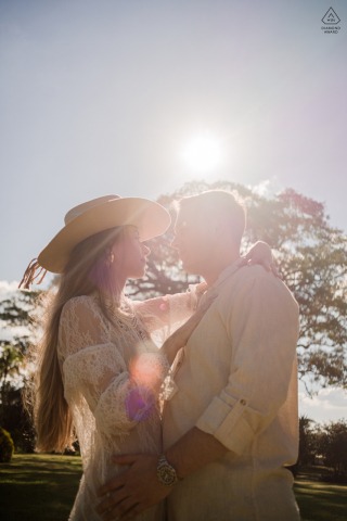 In São Paulo, the tall vertical outdoor portrait faces the sun with partial silhouettes and trees in the background, giving the couple an airy, striking, and romantic feel.