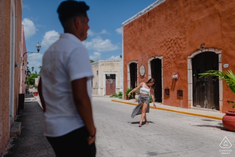 Colorful Colonial Streets Frame The Couple In Valladolid, Yucatán, Mexico Engagement Portrait Pre-wedding engagement portrait of a couple on a vibrant colonial street in Valladolid, Yucatán, Mexico, framed by colorful historic buildings.