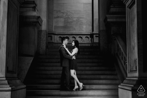 Marble Staircase Elegance Frames The Couple Inside Philadelphia City Hall During Their Engagement Session An engaged couple shares a quiet embrace on the elegant marble staircase inside Philadelphia City Hall during their pre-wedding portrait session.