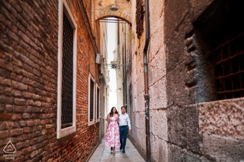 A couple walks hand in hand through a narrow street in Venice, Italy, during a romantic pre-wedding engagement photo session.