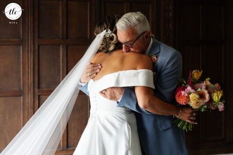 At Fanhams Hall, the father of the bride warmly embraces his daughter, providing a moment of comfort, love, and support during her wedding day.