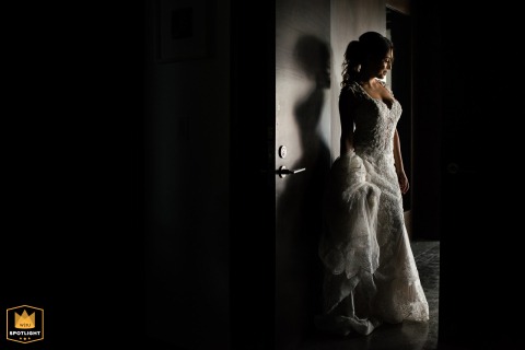 In Cabo San Lucas, a bride's portrait captures her standing solo in a door opening, in profile, side-lit with minimalist, off-centered framing.