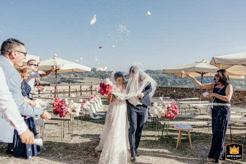 At Sorrivoli Castle, Cesena, Italy, the spouses are playfully protected by the bride's veil during confetti time.