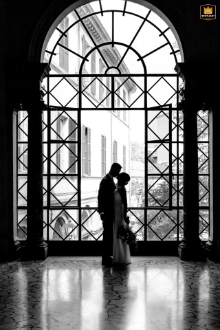 At City Council, Forlì, Italy, a black and white silhouette captures the loving spouses kissing in front of an ancient glass window.