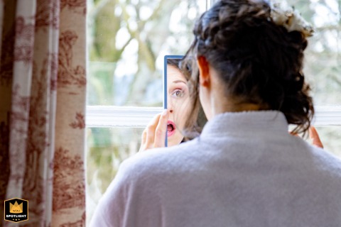 In Roussillon-en-Morvan, the bride stands before a mirror, captured from behind by a WPJA photographer.