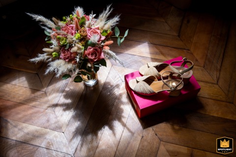 At Château de Millery-Autun, a colorful detail shot captures the bride's bouquet and shoes, illuminated by strong window light.