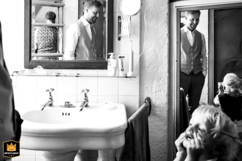 At Château de Ménessaire, the groom and his son prepare, captured in a black and white shot with many reflections in mirrors.
