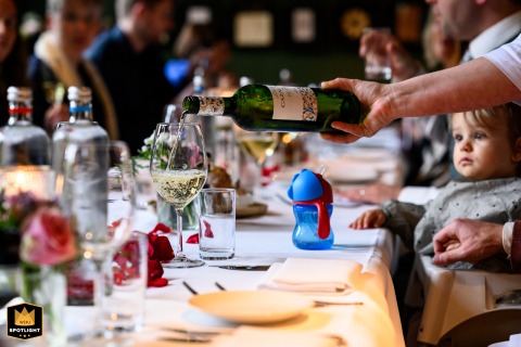 At Reception Venue Den Dungen, white wine is poured into a glass, as a little girl in the background stares, her blue and red water bottle nearby.