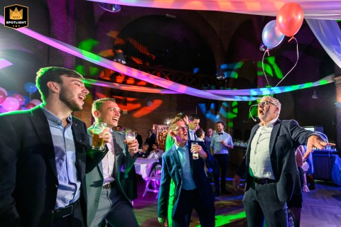 At Wedding Venue Willibrordhaeghe, a guest on the dance floor wears balloons on his glasses in a colorful action shot.