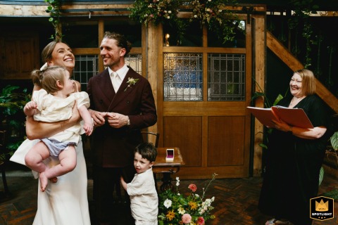 At Clapton Country Club, London, the couple exchanges vows with their young children in their arms and clinging to their legs.