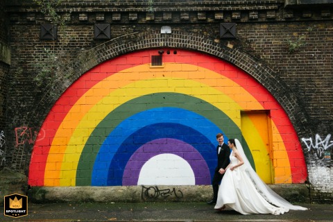At 100 Barrington, Brixton, the newlyweds walk past a vibrant rainbow mural on their wedding venue's wall.