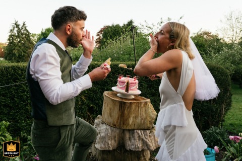 At their family home in the Cotswolds, England, the couple cuts their cake, both using hands to clean their faces and hands.