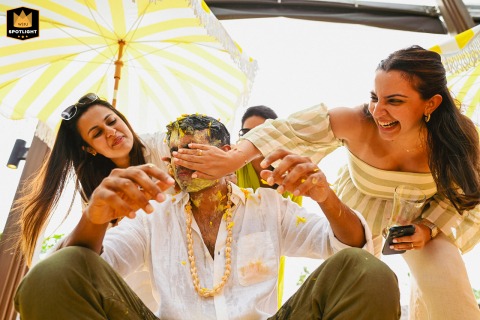 At JW Marriott, Phuket, the groom is playfully covered in turmeric for the Haldi ceremony, amidst laughter and fun.