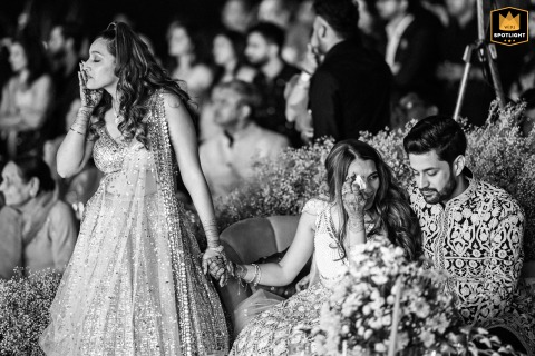 A WPJA wedding photo: During the sangeet at Novotel, Jaipur, two daughters cry as the groom comforts the bride, an emotional message from their deceased father playing.