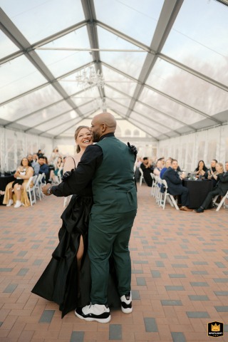 At Hidden Creek Estates, Roscoe, IL, a vertical shot captures the couple's joyful first dance under the geometric glass roof of the venue.