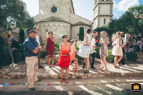 In Marseille, France, guests wait outside the church for the bride and groom, forming a layered scene with multiple individual stories.