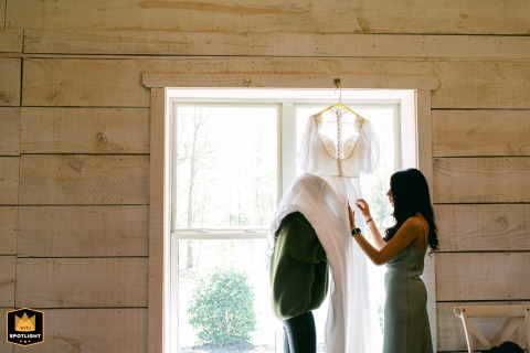 Bride repairs her vintage wedding dress from inside, focused and calm, preparing at Khoury Farms, Auburn, Georgia, intimate moment.