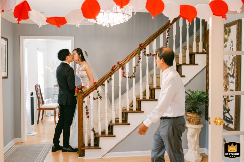 Bride and groom share emotional first look in bride’s parents’ Duluth home, while uncle walks through background, candid moment.