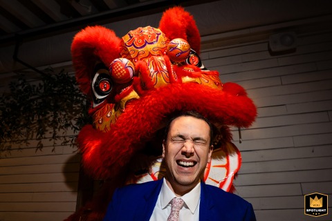At Brentsville Hall, VA, a Chinese lion dance takes place during the wedding reception, with a red dragon head on the laughing groom.