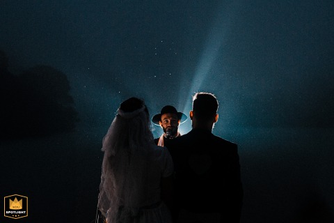 At Espaço Dieters – São Bernardo do Campo, Brasil, a night outdoor ceremony features the officiant centered between the backlit couple.
