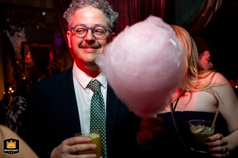 At The Peninsula Istanbul Hotel, an elderly male guest with glasses and a mustache holds a glass and a cotton candy, staring to his right.