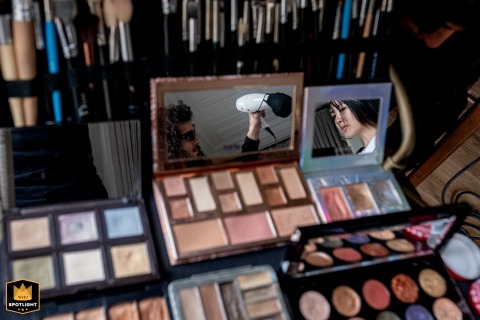 At Six Senses Kocataş Mansions Istanbul, a makeup accessory reflects a hairdresser with long curly hair and sunglasses, alongside the bride, surrounded by makeup.