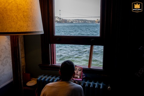 At Kıbrıslı Yalısı, a mansion on the Bosphorus, a woman crouches to do her makeup with a small mirror, enjoying the Istanbul water view.
