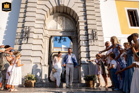 At Simi Panormitis Monastery, a bride and groom hold each other as they leave the church, showered with confetti by guests.