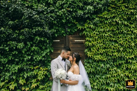 Next to the hotel in West Pomeranian, Poland, the bride and groom stand face-to-face during their reception session, framed by an ivy wall of green foliage.