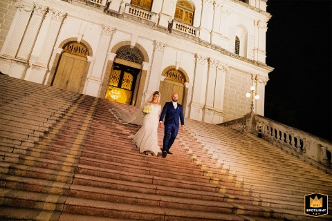 Bride and groom joyfully descend the grand stairs of Basílica Nossa Senhora das Dores in Porto Alegre, radiating happiness.
