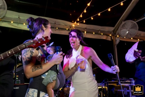 Bride and her friend joyfully sing with the live band at Mackey House wedding reception in Savannah, Georgia.