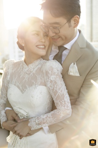 At Mandarin Oriental Bangkok, a smiling bride is embraced from behind by the groom in a washed-out, intimate portrait.