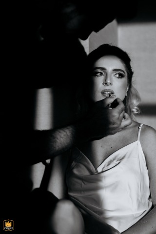 A black and white detail from São Paulo: A bride gets lipstick applied, with striking interplay of sunlight and shadows, captured by a WPJA photographer.