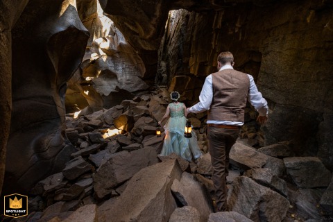 A WPJA wedding photo: In Grotto Cave, Aspen, Colorado, a non-traditional couple descends into a cave, illuminated by lanterns they hold.
