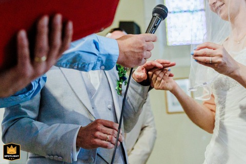 Close-up of bride and groom's hands during vows at a local church in Messanges, France, capturing the symbolic gesture and emotional charge.
