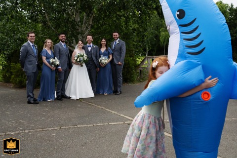Young girl joyfully hugs a man in a playful shark costume at London Wetland Centre during a wedding celebration.