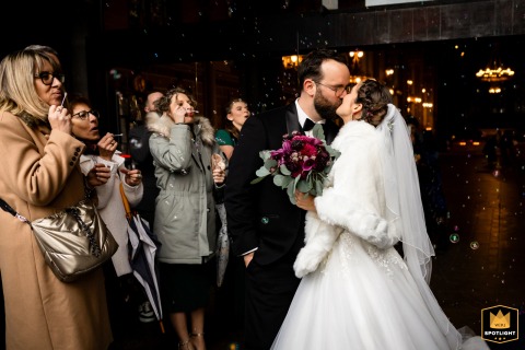 Bride and groom sharing a kiss at the exit of Saint Bruno church in Voiron, Isère, France, after wedding ceremony.