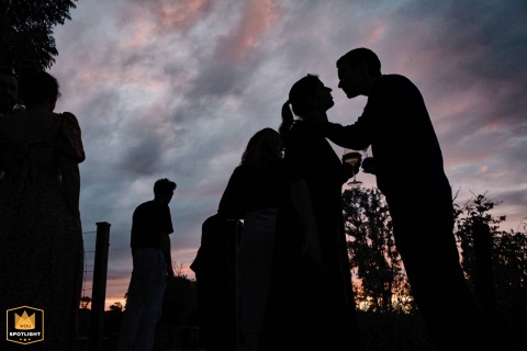 In Haute-Saône, France, guests are silhouetted against a dramatic sky during the cocktail hour, captured by a WPJA photographer.